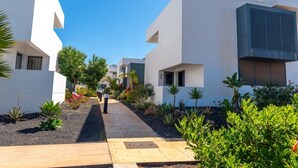 A modern building with a clean, white exterior and a paved walkway. - Cozy apartment with pool (CN)