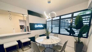 A modern kitchen with a marble countertop, a round dining table with chairs, and a potted plant.