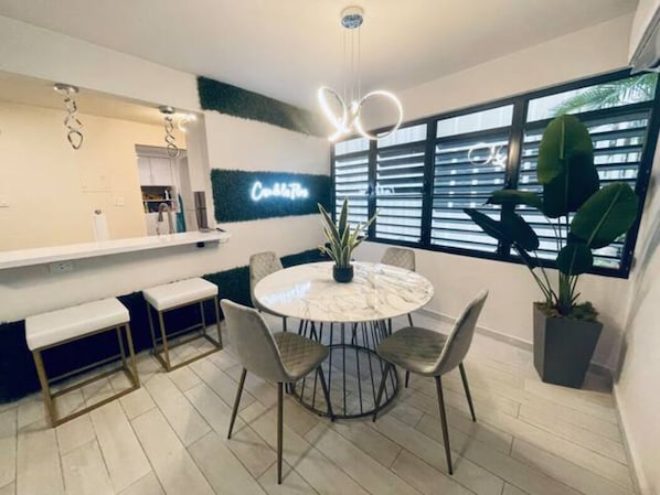 Een moderne keuken met een marmeren aanrecht, een ronde eettafel met stoelen en een potplant.