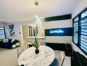 Een moderne woonkamer met een marmeren salontafel, een bank en een neonbord aan de muur.