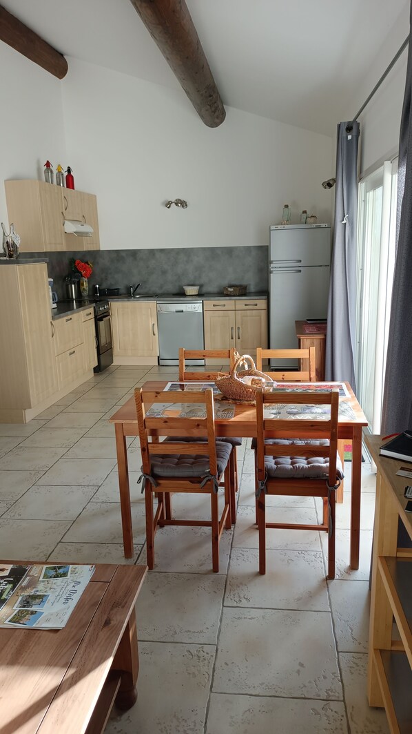 A spacious kitchen with wooden cabinets, a dining table with chairs, and a refrigerator.