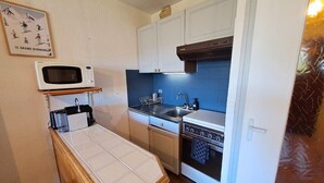 A compact kitchen with a microwave, stove, sink, and a small countertop. - Studio at the foot of the ice rink (Le Grand-Bornand)