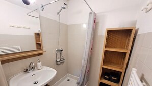 A bathroom with a shower, a sink, and wooden shelves. - Studio at the foot of the ice rink (Le Grand-Bornand)