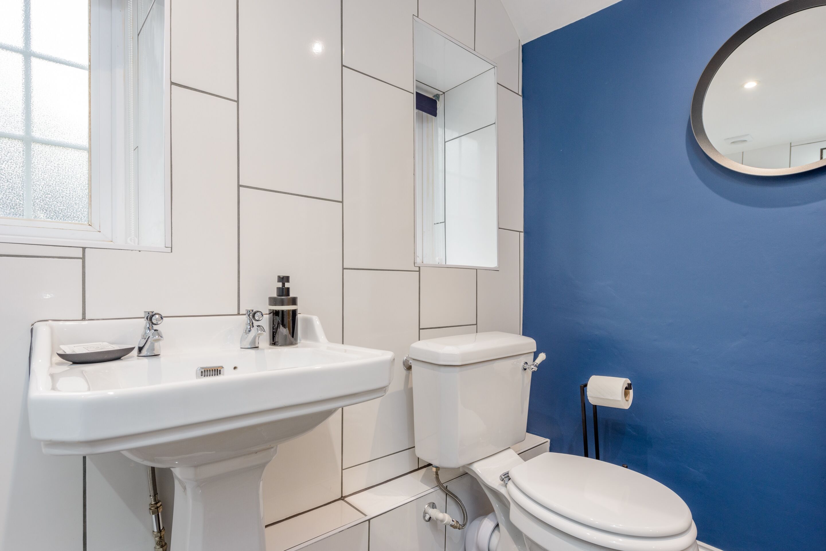 A bathroom with a white sink, toilet, and blue wall.