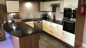 A modern kitchen with a black countertop, white cabinets, a built-in oven, and a microwave. - Romantic / Valentines Lodge by Loch Lomond (Alexandria)