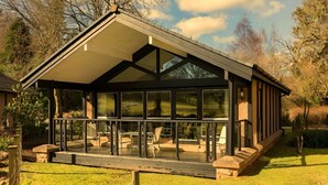 A modern house with a glass conservatory, a wooden deck, and a garden. - Romantic / Valentines Lodge by Loch Lomond (Alexandria)