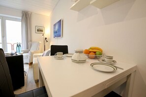 Enjoy a self-service breakfast at this hotel room's dining area, featuring a table set with a bowl of fruit, teapot, and cup.