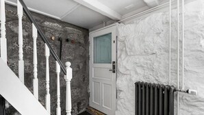 A staircase with white balusters, a stone wall, a white door with a glass panel, and a radiator. - Fantastic Studio in the city center B3 (Reykjavík)