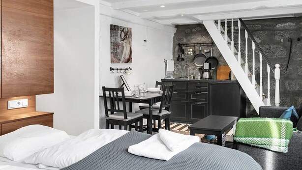 A compact room with a bed, a small dining table, a kitchenette, and a staircase. - Fantastic Studio in the city center B3 (Reykjavík)