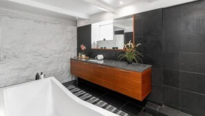 A modern bathroom with a marble wall, dark tiled walls, a wooden vanity, and a large mirror. - Fantastic Studio in the city center B3 (Reykjavík)