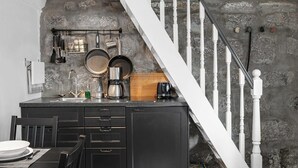 A kitchen with a stone wall, a white staircase, and a black countertop. - Fantastic Studio in the city center B3 (Reykjavík)