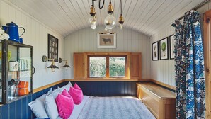 Un dormitorio acogedor con una cama de madera, una ventana con vistas y un aparador con espejo.