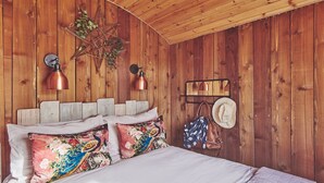 A wooden bedroom with a bed, pillows, a star decoration, and a hat on a shelf.