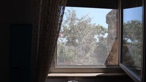 Una finestra con vista su alberi e una formazione rocciosa.
