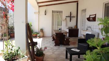 Un patio con tavolo e sedie di legno, piante in vaso e pavimento in pietra.