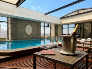 Un espace aménagé au bord de la piscine, avec une table, une bouteille de champagne et un carnet.