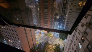 Um edifício alto com vários andares e janelas, visto de um prédio mais baixo.