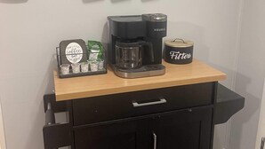 A kitchenette with a coffee maker, a coffee mug, and a coffee pod holder.
