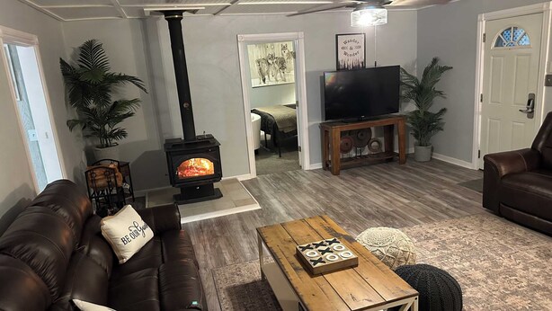 A cozy living room with a fireplace, leather sofa, wooden coffee table, and a television on a stand.
