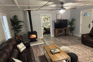 A cozy living room with a fireplace, leather sofa, wooden coffee table, and a television on a stand.