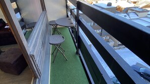A balcony with a green artificial turf floor, a small round table, and a chair. - High standing, FOOT OF THE SLOPES and summer activities (Les Menuires)