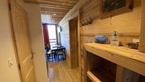 A wooden interior with a dining area, a wooden shelf with a bottle, and a painting on the wall. - High standing, FOOT OF THE SLOPES and summer activities (Les Menuires)