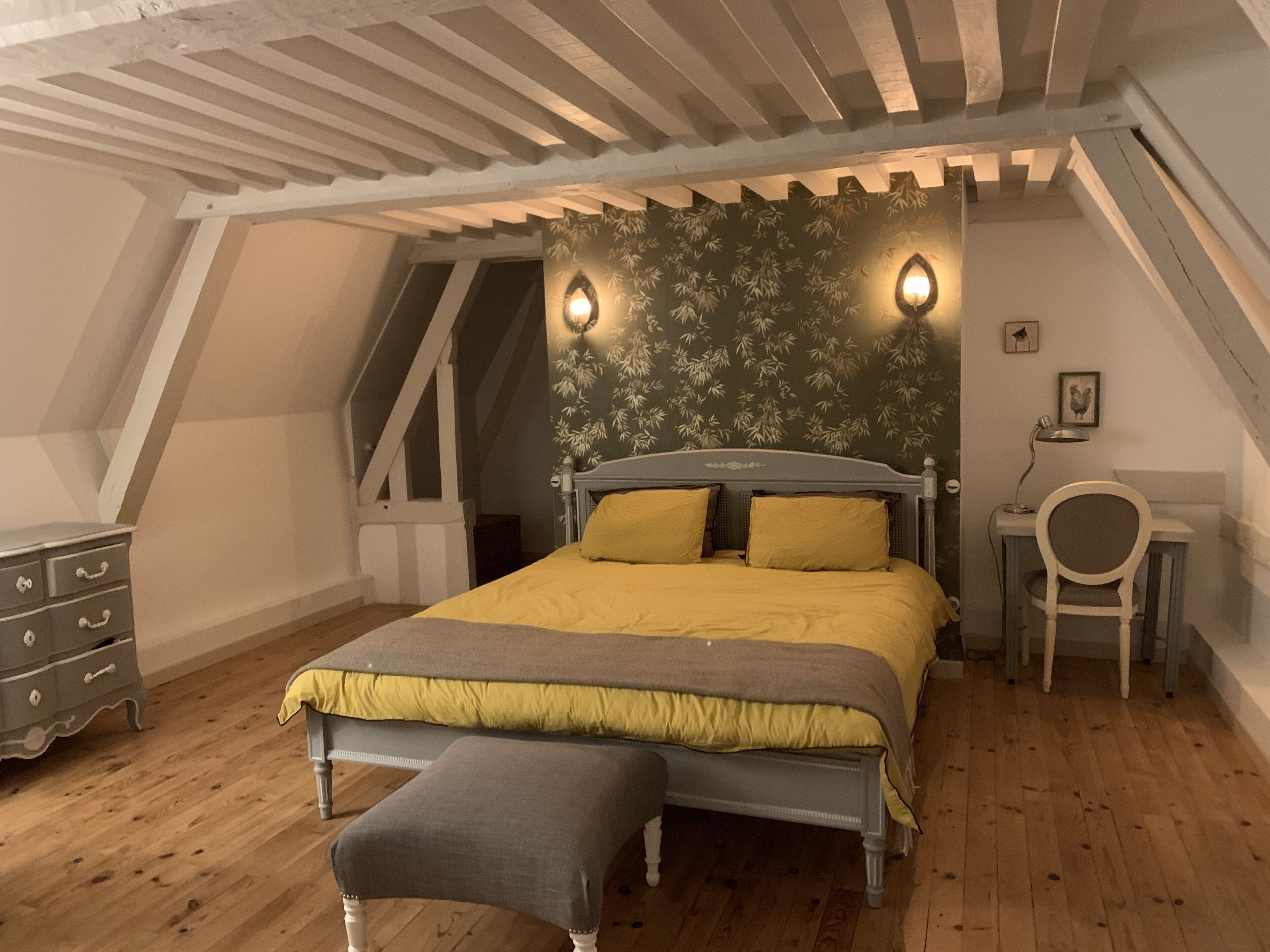 Un dormitorio con cama, banca, cómoda y escritorio con silla.