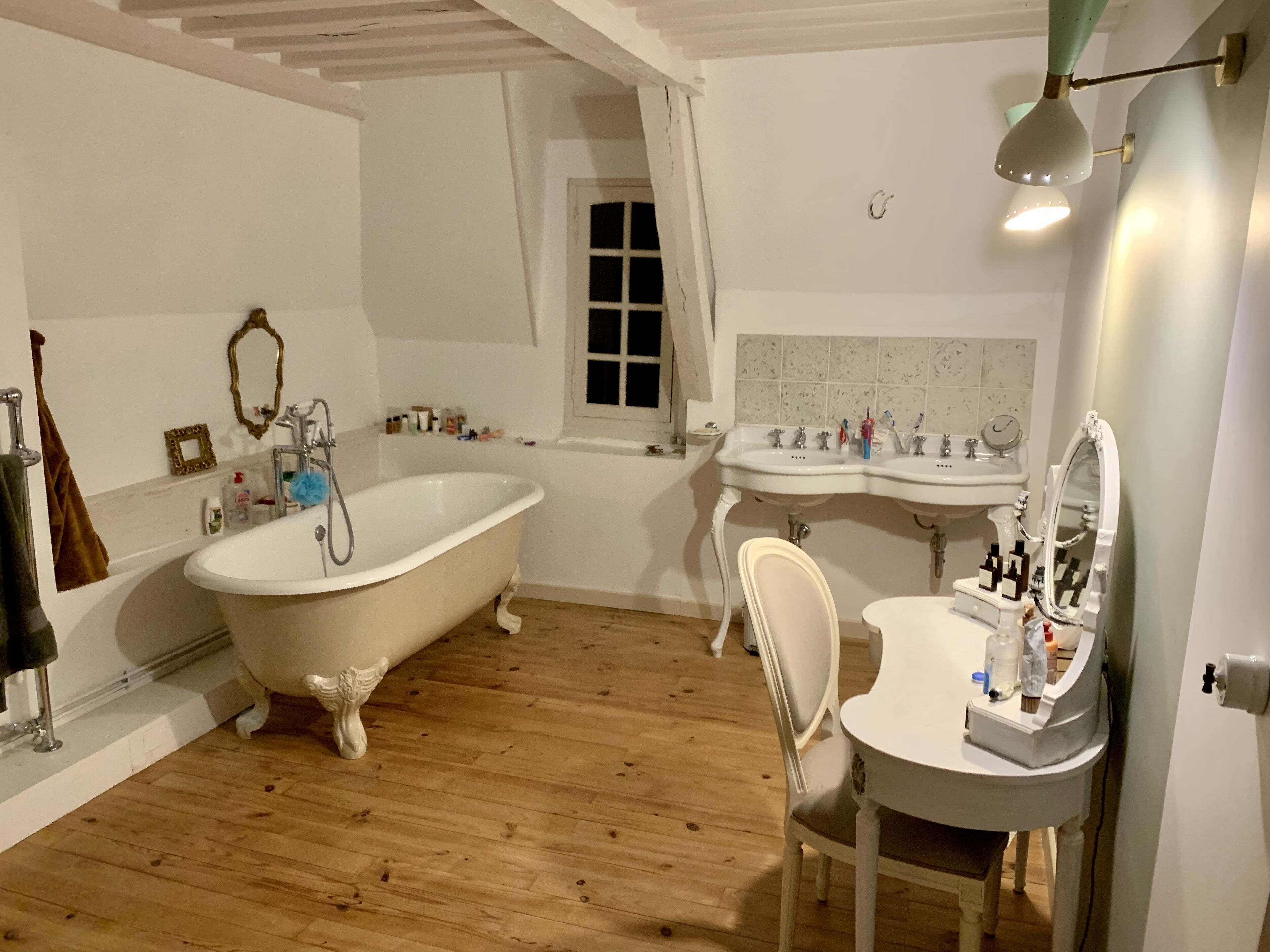 Ein Badezimmer mit Badewanne auf Pfotenfüßen, zwei Waschbecken, einem Schminktisch mit Spiegel und Holzboden.