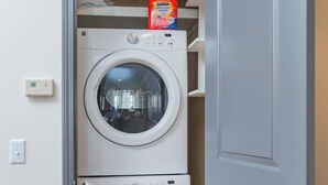 A laundry room with two stacked front-loading washing machines and a door to the right. - 2 Lofts on Broadway Strip - Sleeps 10 (Nashville)