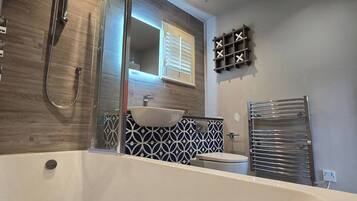 A modern bathroom with a freestanding bathtub, a glass-enclosed shower, and a vanity with a mirror.