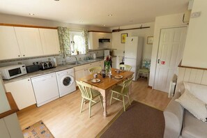 A compact kitchen with a dining area, including appliances like a microwave, dishwasher, and washing machine.