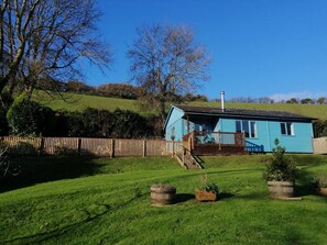 A single-story blue house with a porch, surrounded by a wooden fence and a grassy yard.