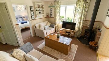A cozy living room with a sofa, a coffee table, a TV, and a fireplace.