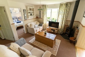 A cozy living room with a sofa, a coffee table, a TV, and a fireplace.