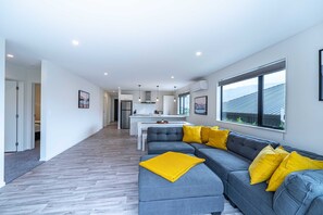 Relax in this stylish living area with a sofa, dining table, and kitchen, offering a view of the outdoors.