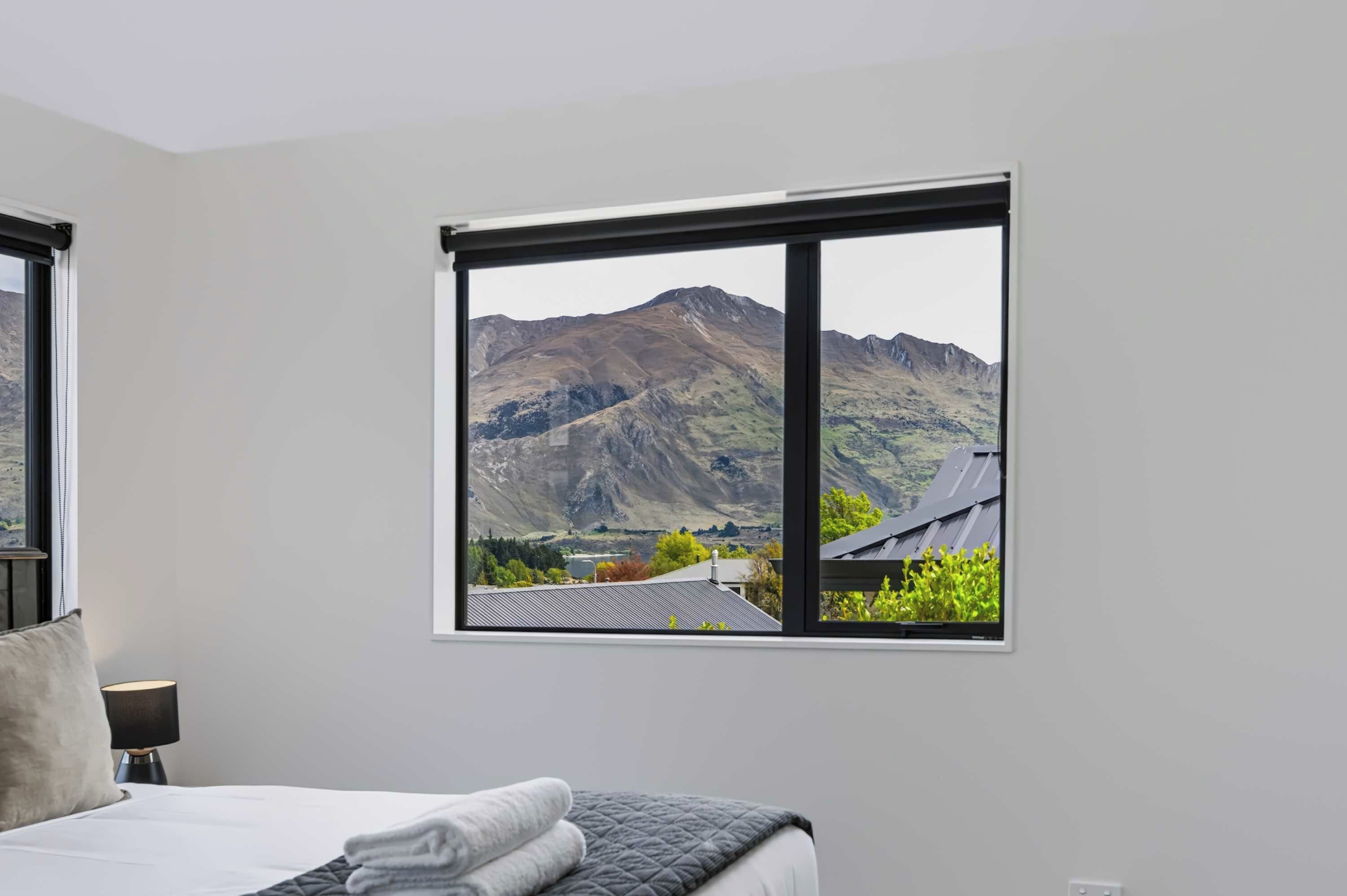 A bedroom with a large window offering a mountain view.