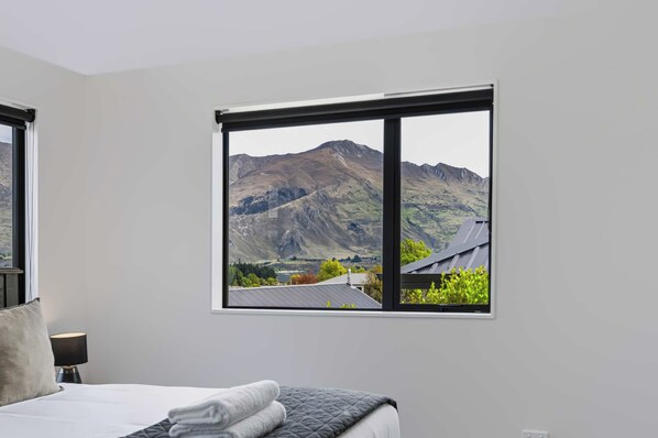 A bedroom with a large window offering a mountain view.
