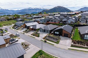 A residential area with modern houses, a main road, and a mountain range in the background.