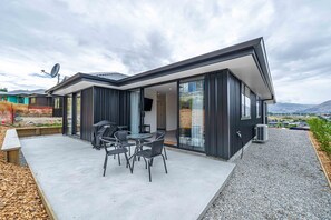 Une maison moderne dotée d’un patio, d’un espace salon extérieur et offrant une vue sur la campagne.