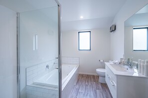 Une salle de bain moderne dotée d’une douche à parois de verre, d’une baignoire sur pieds, de toilettes et d’un meuble-lavabo avec un miroir.