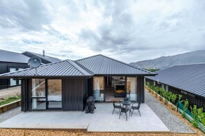Relax in a serene environment with a spacious patio area, seating arrangement, and beautiful garden views.