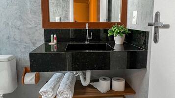 Un baño con un espejo grande, encimera negra y una planta en maceta.