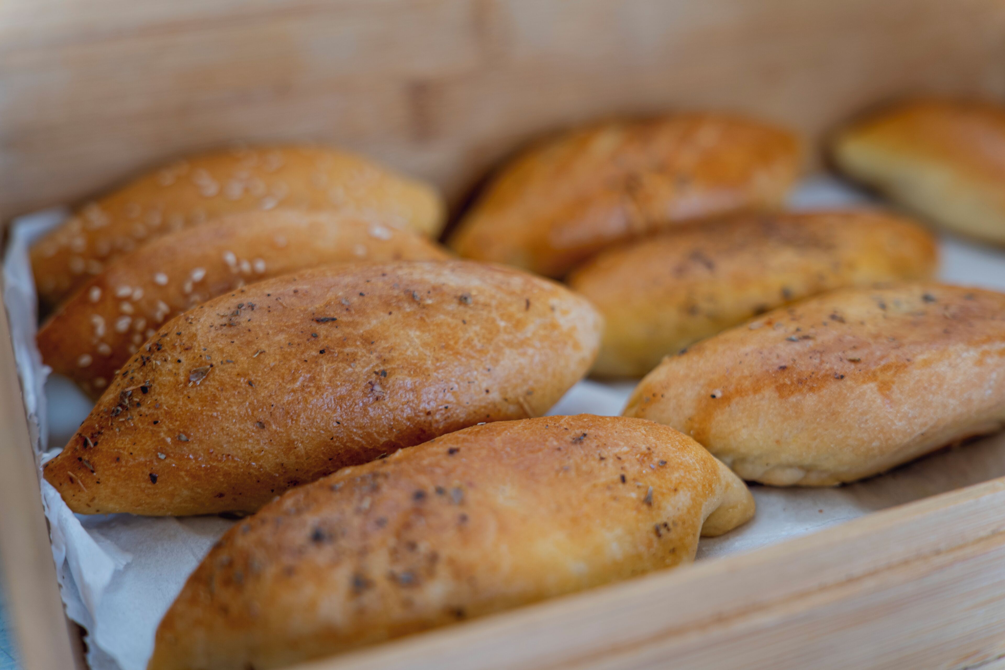 Eine Holzkiste mit mehreren länglichen Gebäckstücken, belegt mit Sesam.