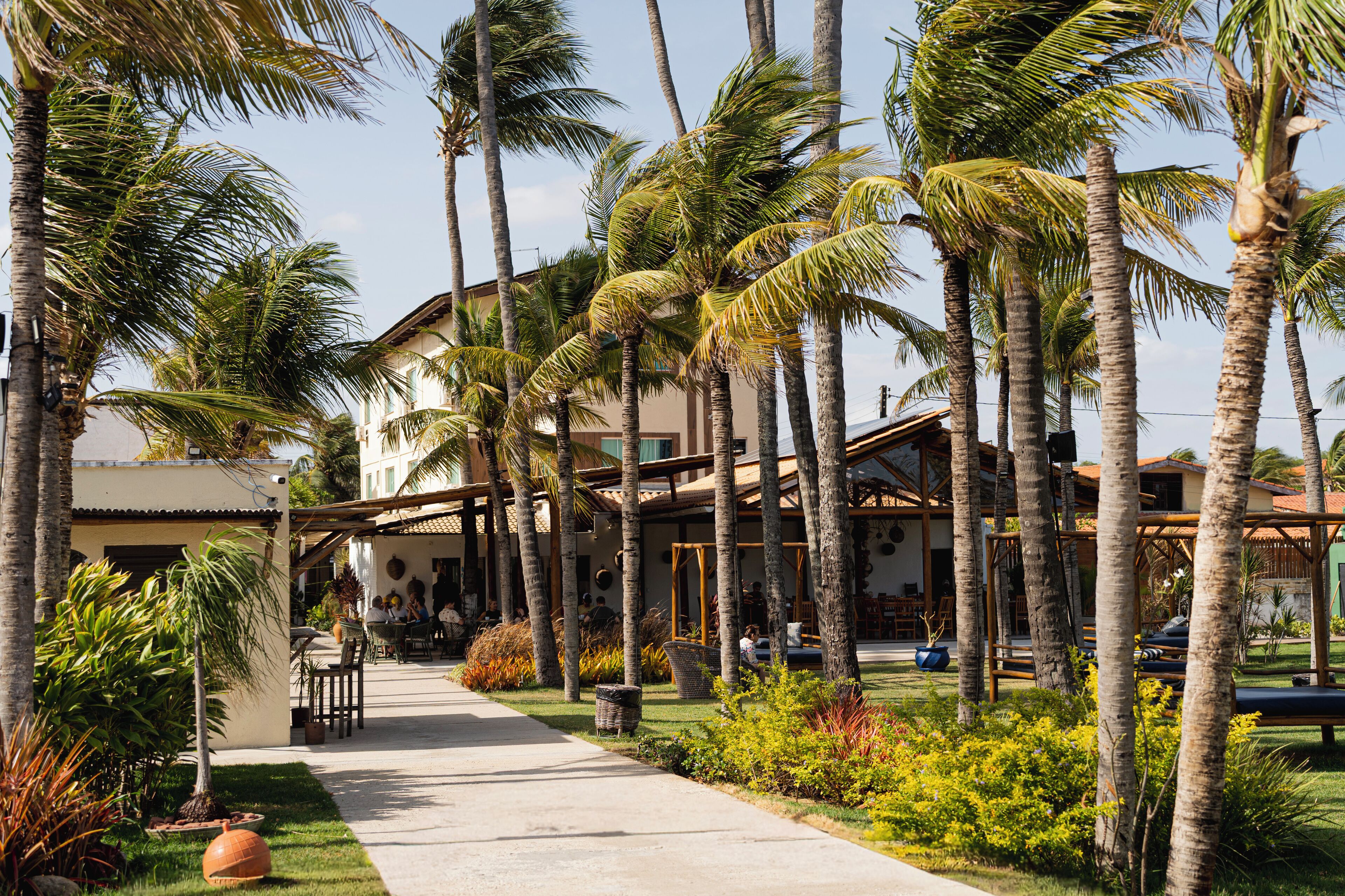 A resort with a paved walkway, palm trees, and a building with a covered patio area.