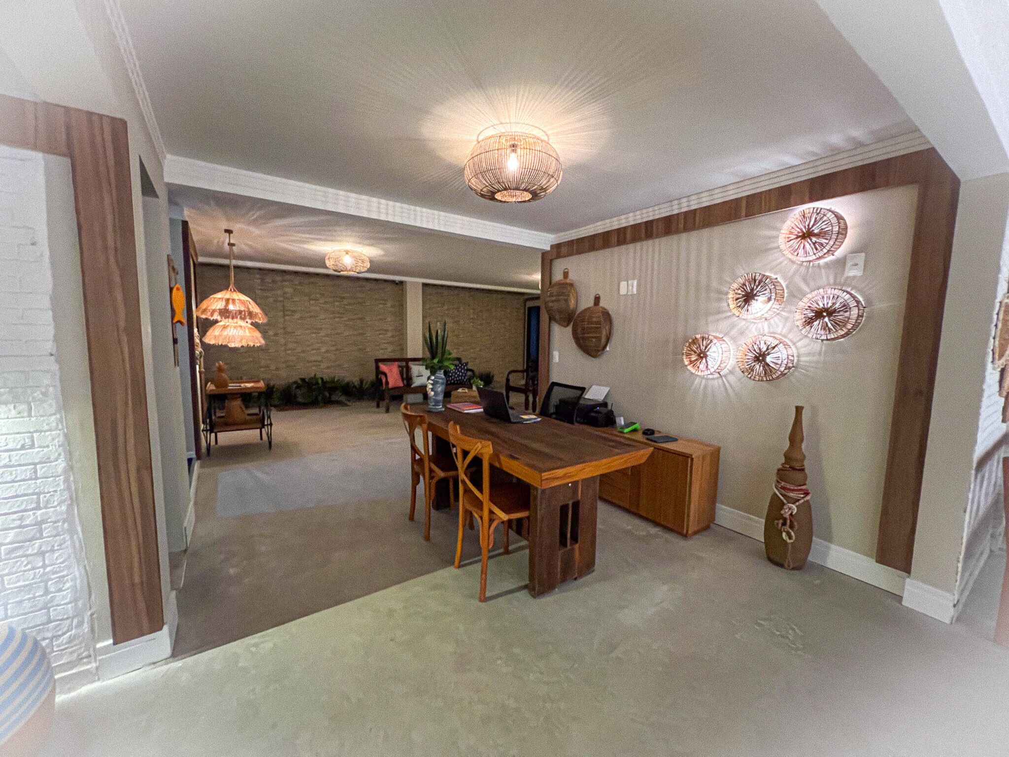 A spacious dining area with a wooden table and chairs, a brick wall, and decorative wall art.