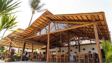 An outdoor dining area with bamboo structures, wooden tables, and chairs.
