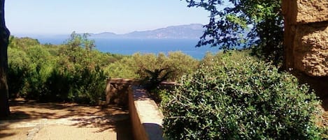 A pathway leading to a scenic overlook with a view of the sea and distant hills.