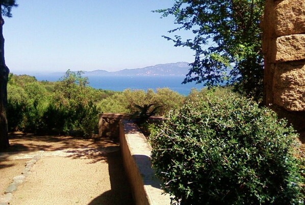 A pathway leading to a scenic overlook with a view of the sea and distant hills.