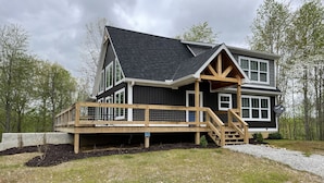 A two-story house with a wooden deck and a satellite dish.