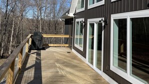 A modern two-story house with large windows and a wooden deck.